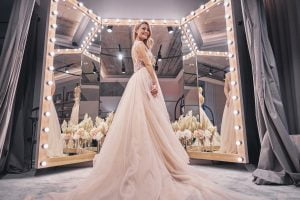 exited about her wedding. full length of attractive young woman wearing wedding dress and smiling while standing in bridal shop